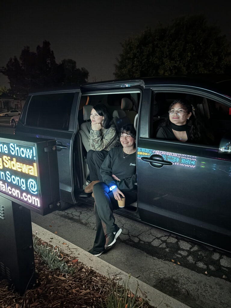 Visitors beside the Lights on Falcon song-request sign on Falcon Avenue